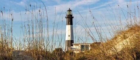 A lighthouse surrounded by tall grass and sand.