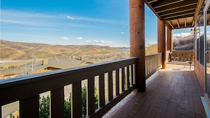 Un balcone in legno con vista su una valle e colline lontane.