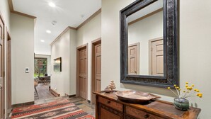 A hallway with a wooden cabinet, a mirror, and a patterned rug.