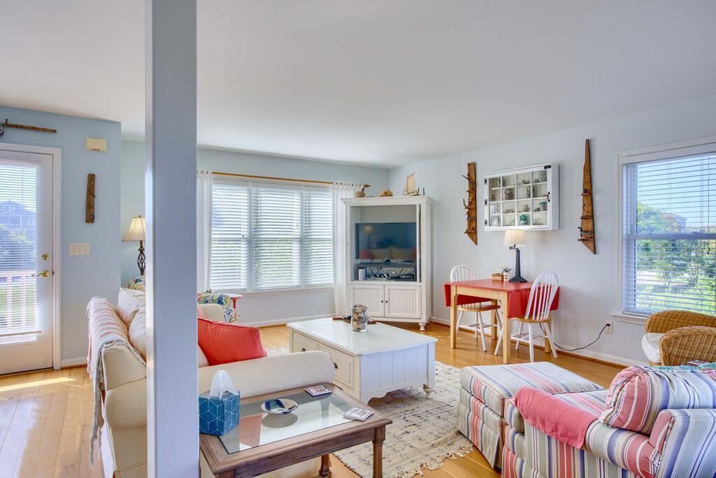 A cozy living room with a sofa, a coffee table, a dining table with chairs, and a television.