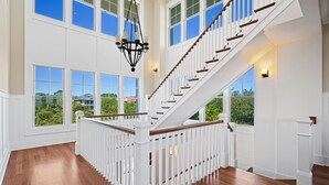 Un intérieur spacieux agrémenté d’un magnifique escalier, de grandes fenêtres et d’un lustre.