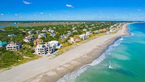 Un quartier résidentiel situé sur la côte, avec des propriétés donnant sur la plage, une plage de sable et un océan d’un bleu limpide.