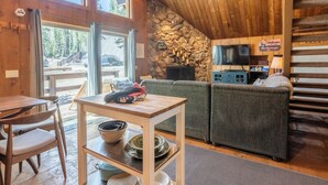 Een gezellig houten interieur met een stenen openhaard, een televisie en een houten eettafel.