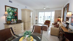 A spacious living room with a dining area, a large painting, and a view of the city. - Spacious One Bedroom with Pool View! (Bonita Springs)