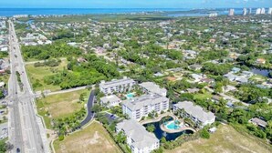 An aerial view of a coastal residential area with a prominent road, a large hotel with multiple buildings, and a swimming pool. - Spacious One Bedroom with Pool View! (Bonita Springs)