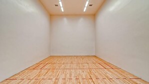 Una cancha de squash con piso de madera y líneas delimitadoras rojas.