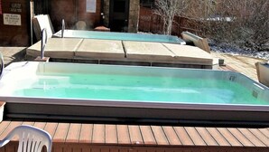 Zona de hidromasaje al aire libre con terraza de madera, una silla de plástico y un letrero que prohíbe fumar.
