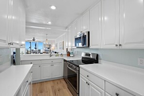 A modern kitchen with white cabinetry, a stainless steel stove, and a microwave.