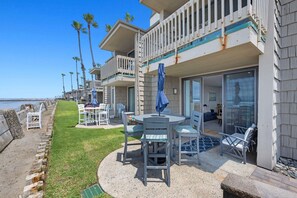 A beachfront property with a patio area, outdoor seating, and a view of the ocean.