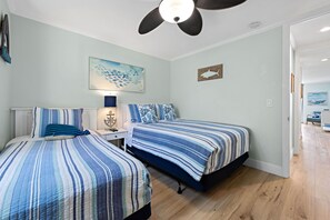 Ein Schlafzimmer mit zwei Betten, einem Deckenventilator, Kunstwerken und einem Holzboden.
