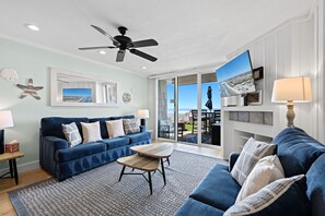 A living room with a blue sofa, a wooden coffee table, and a ceiling fan.