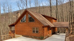 Une cabane en rondins dotée d’une grande véranda à l’avant, d’une cheminée et de fondations en pierre.