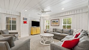 A living room with a grey sofa, a yellow cabinet, a TV, and a ceiling fan. - Eclectic Creek Front Retreat (Georgetown)