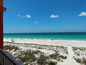 Uma praia com céu claro e águas azul-turquesa.