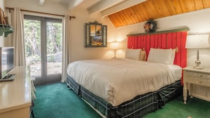 A bedroom with a bed, a nightstand, a lamp, a mirror, and a view of the outdoors. - Chalet #14, Great Family Chalet Close the the Main (Mammoth Lakes)