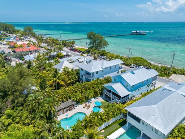 A coastal resort with multiple buildings, a swimming pool, and a pier extending into the ocean.