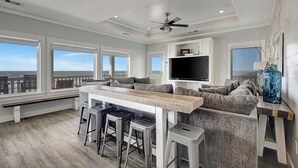 Une cuisine moderne dotée d’un bar, de grandes fenêtres et d’un ventilateur de plafond.