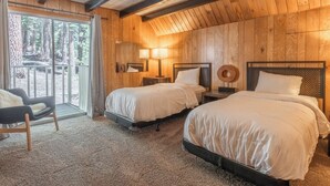 A wooden cabin room with two beds, a chair, and a large window overlooking a forest. - Chalet #12, Slope Side Ski in Ski Out Spacious Fam (Mammoth Lakes)