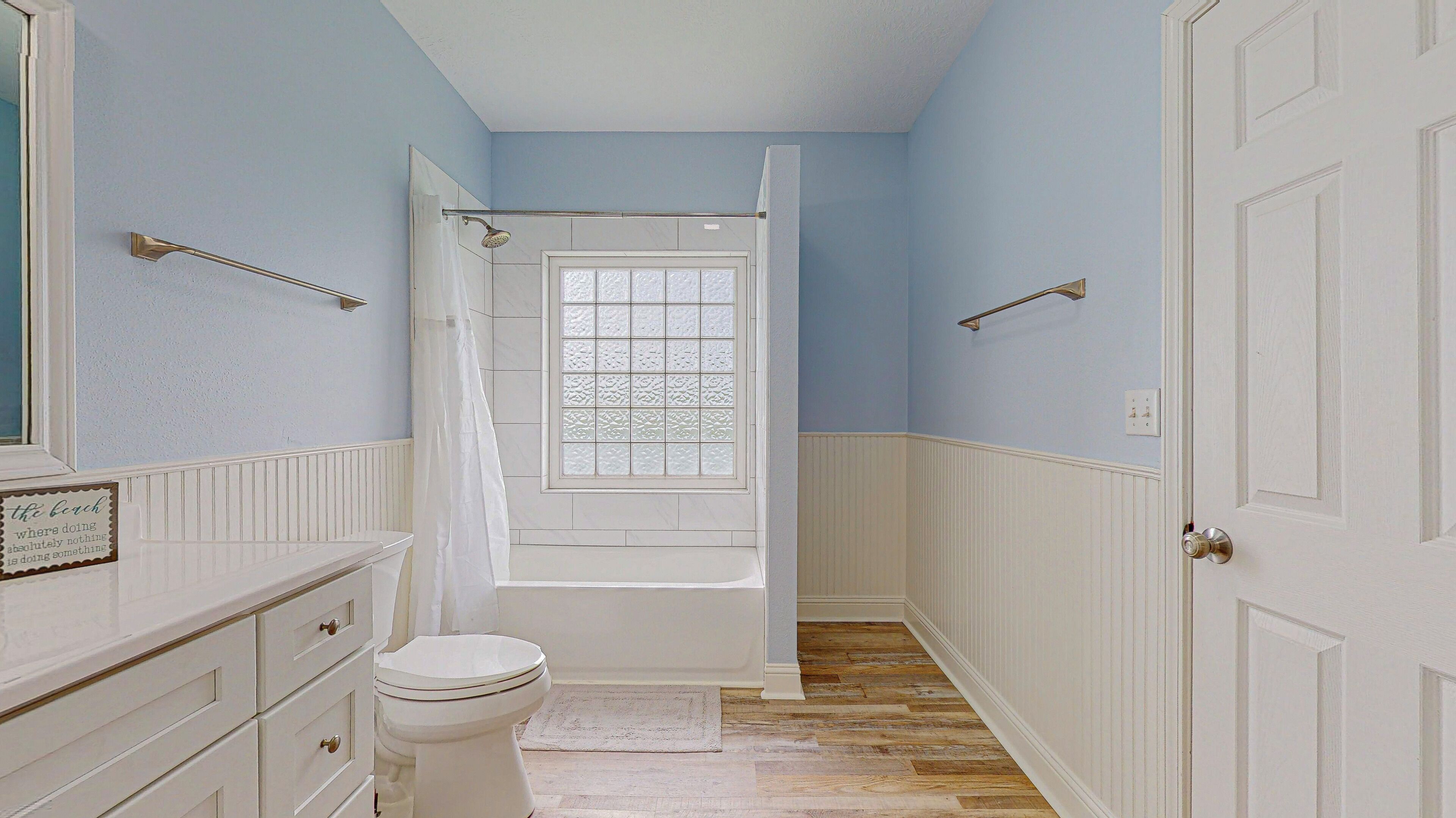 A bathroom with a bathtub, toilet, and a window with a shower curtain.