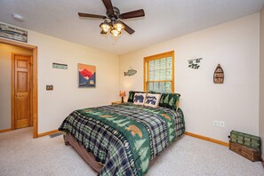 Une chambre à coucher avec un lit, un ventilateur de plafond, une fenêtre et des éléments décoratifs sur les murs.
