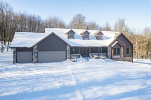 A two-story house with a stone facade, multiple garage doors, and a snow-covered roof.