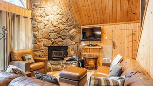 Un salon chaleureux avec un mur en pierre, un canapé en cuir et une cheminée.