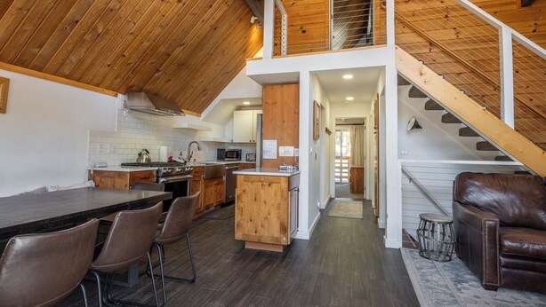 Una cocina amplia con una isla central, techo de madera y una escalera que lleva a un nivel superior.