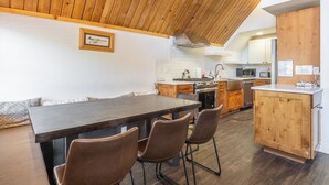 Una cocina moderna con armarios de madera, una mesa de comedor con sillas y una estufa visible.
