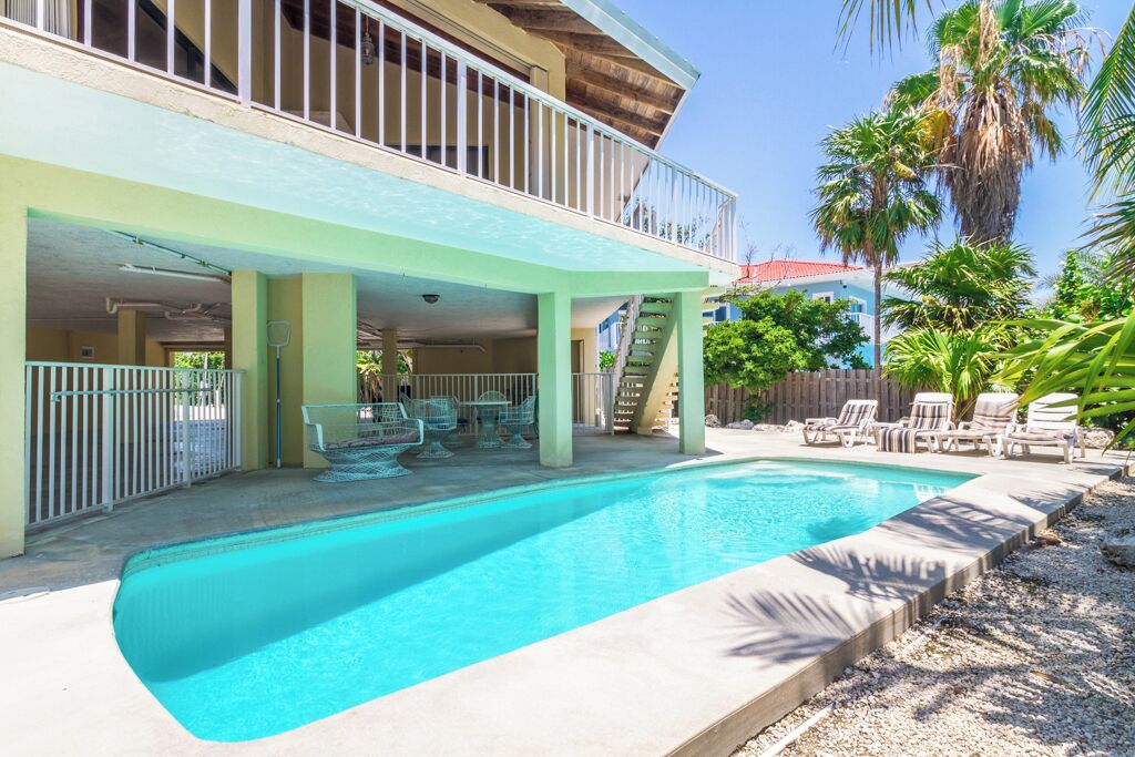 Une piscine avec des chaises longues et un espace patio couvert.