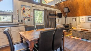 A cozy cabin interior with a wooden dining table, chairs, a fireplace, and a sofa. - Chalet #5, Ski In Ski Out Chalet at the Main Lodge (Mammoth Lakes)
