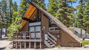 A cabin with a sloped roof, large windows, and a wooden deck with stairs leading to the entrance. - Chalet #5, Ski In Ski Out Chalet at the Main Lodge (Mammoth Lakes)
