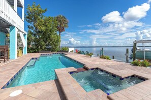 A pool area with clear blue water, a boat docked on the right, and a view of the water body in the background.