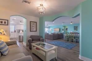 A modern living room with a sofa, coffee table, and a dining area with chairs and a table.