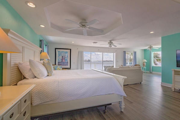 Quarto com cama grande, ventilador de teto e vista para o exterior.