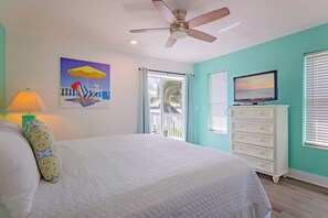 A bedroom with a bed, a ceiling fan, a TV, and a window with blinds.