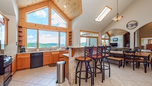 A spacious kitchen with large windows, wooden cabinetry, and a bar area.