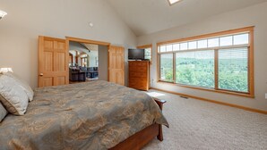 A bedroom with a large bed, a TV, a wardrobe, and a skylight.
