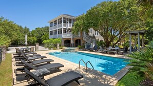 A pool area with lounge chairs, a hot tub, and a two-story building with a balcony. - Sprawling Home Close to the Beach (Georgetown)