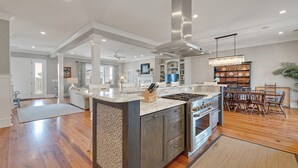 A spacious kitchen with a large island, stainless steel appliances, and a chandelier. - Sprawling Home Close to the Beach (Georgetown)
