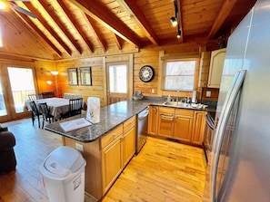 Cozy cabin-style kitchen with a central island, sink, and dining area.