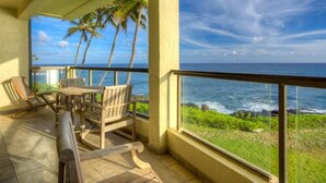 Un balcon doté de mobilier en bois et offrant une vue sur l’océan.