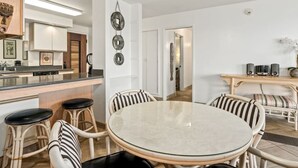 Une cuisine moderne dotée d’un îlot central, de tabourets de bar et d’un coin repas avec une table ronde et des chaises à rayures.