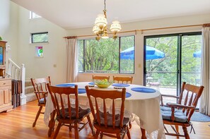 A dining area with a round table, wooden chairs, and a chandelier.