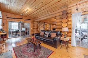 A log cabin interior with a leather sofa, a wooden coffee table, and a patterned rug.