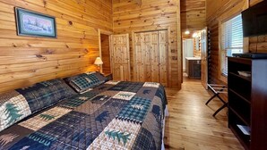 Een houten blokhut van binnen met een bed, een bureau en een televisie.
