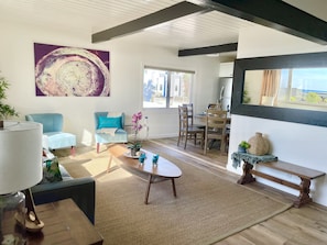 Un salón moderno con un sillón azul, una mesita de centro y un cuadro abstracto grande.