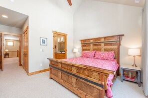 A bedroom with a wooden bed, a nightstand, a mirror, and a door leading to another room.