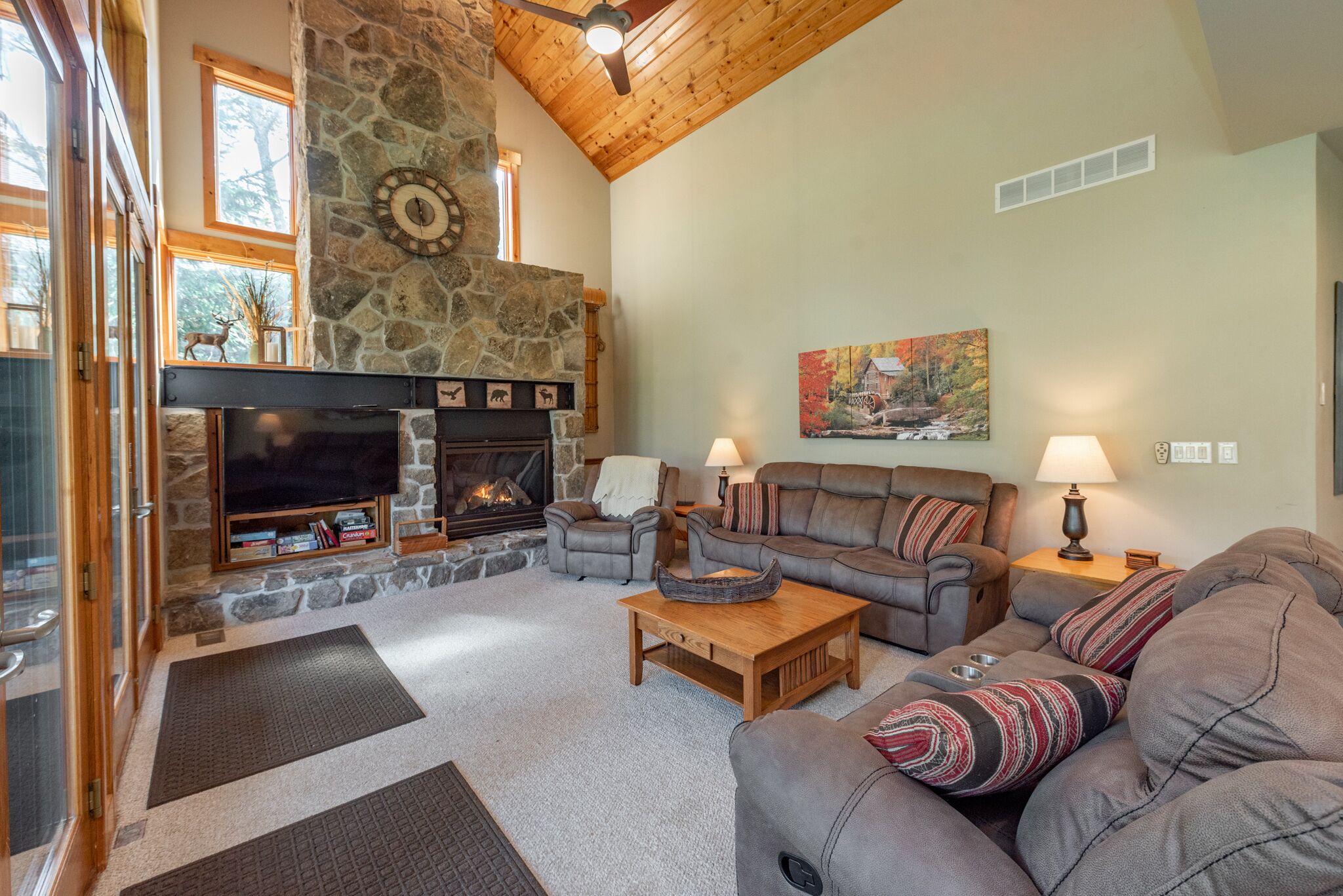 A cozy living room with a stone fireplace, leather sofas, and a television.