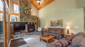A cozy living room with a stone fireplace, leather sofas, and a television.