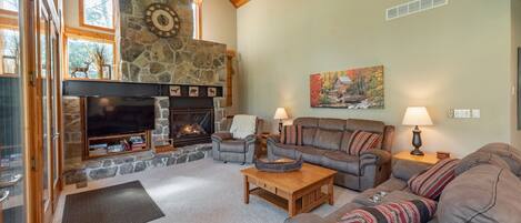 A cozy living room with a stone fireplace, leather sofas, and a television.